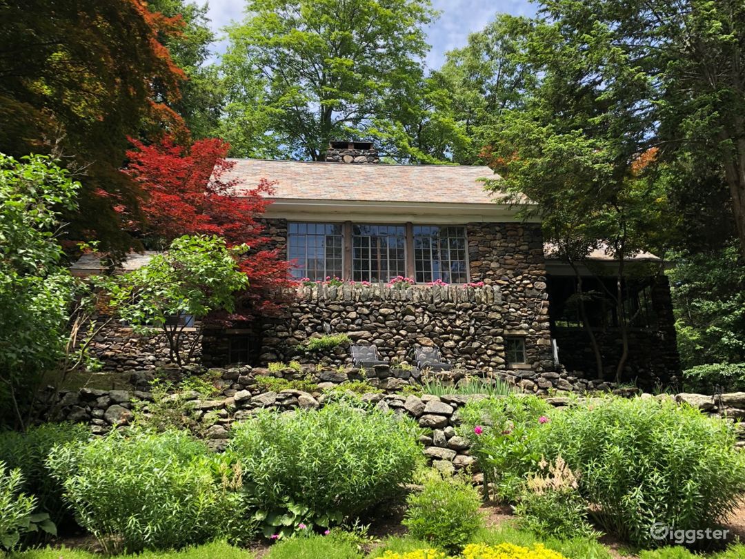 View of the back of the stone cottage. It faces the main house, and is atop a hill. 